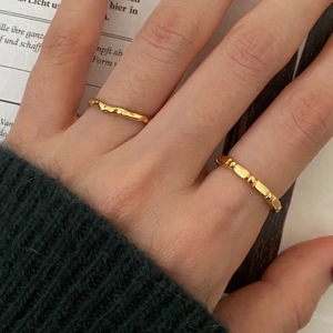 Detail of minimalist gold irregular lava ring and beaded band on model fingers