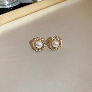 Dettaglio orecchino a perno dorato con perla centrale e pavé di strass su metallo intrecciato