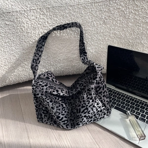 Close-up of leopard print tote bag on wooden floor with side brand label detail