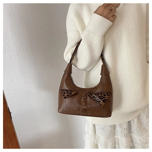 Close-up of brown shoulder bag with leopard print bow detail and decorative buttons