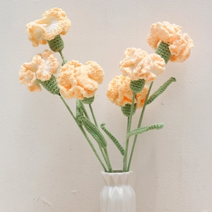 Detailed macro view of hand-knitted light orange carnations made of soft wool yarn