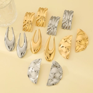 Detailed close-up of textured gold and silver metal hoop earrings on a minimalist background