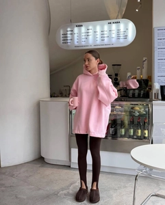 Close-up of pink oversized hoodie with cartoon print and stirrup leggings in a cafe