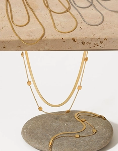 Detail of gold and silver double-layered snake chains with square bead accents