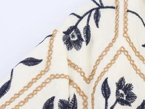 Details von Blumenstickereien und Kettenstich auf cremefarbenem Leinenkleid-Stoff