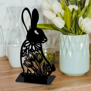 Detail of black acrylic Easter bunny with hollow tulip patterns on wooden desktop
