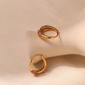 18K gold-plated oval hoop earrings with colorful zircon stones on ceramic display