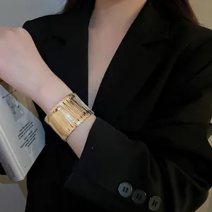 Irregular textured gold bangle bracelet for women styled with a professional black suit