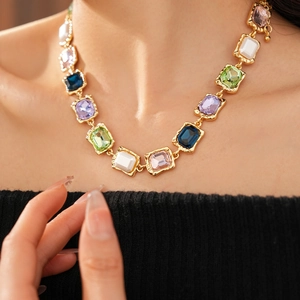 Close-up of vintage gold-plated necklace with colorful rectangular gemstones on model