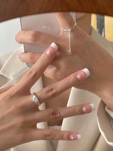 French style press-on nails with pearls and minimalist silver heart rings on a hand