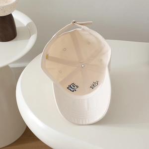 Detail of internal stitching and cute animal embroidery on a beige kids' baseball cap