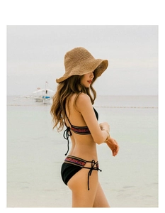 Detail showing hand-woven straw hat brim and colorful ethnic embroidery on bikini