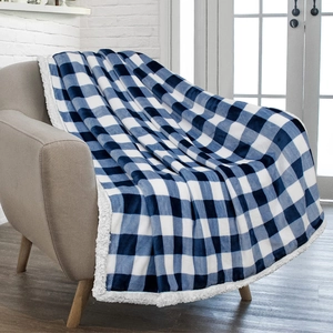 Detail of blue plaid Sherpa fleece blanket draped over a cozy modern armchair