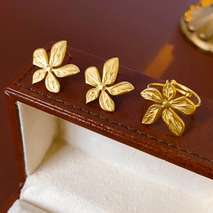 Detail of gold flower earrings and ring set with leaf vein texture on brown leather case