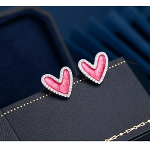 Macro shot of 925 sterling silver heart earrings with pink enamel and diamond accents