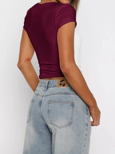 Rear view of a slim fit burgundy short sleeve top paired with light blue denim jeans