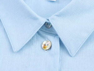 Macro detail of breathable linen shirt collar with natural iridescent shell buttons