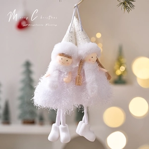 White plush Christmas angel hanging ornaments with sequins and feather skirts in warm bokeh lighting