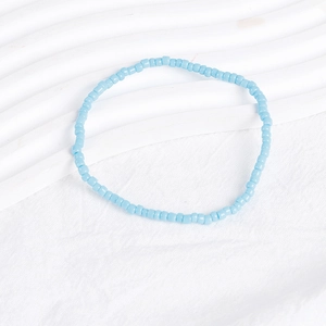 Detailed close-up of sky blue seed bead bracelet on a white textured background