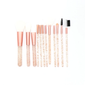 Flat lay of 12-piece makeup brush set with clear glitter handles and rose gold ferrule