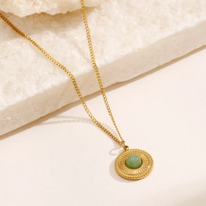 Vintage gold plated necklace with green aventurine sunburst pendant on stone surface
