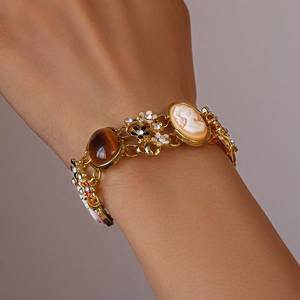 Details eines Vintage-Goldarmbands mit Kamee-Porträt und weißen Emaille-Blumen