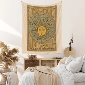 Detail of bohemian tapestry featuring sun god and Trust the Universe typography on wall