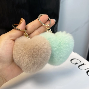 Close-up of heart-shaped faux fur keychains in mint green and light coffee with gold rings