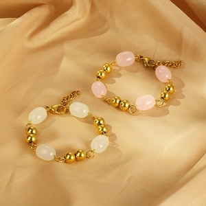 Detail of vintage gold bead bracelets with cream and pink resin oval stones on satin