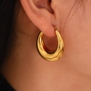 Polished gold teardrop hoop earrings in stainless steel worn on a female model