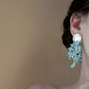 Détail de boucles d'oreilles pampilles en cristal bleu portées par un mannequin