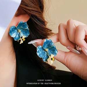 Vintage style floral bee earrings with blue enamel petals and gold accents on a model