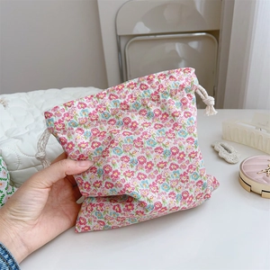 Nahaufnahme einer kleinen rosa geblümten Baumwolltasche mit Kordelzug in der Hand