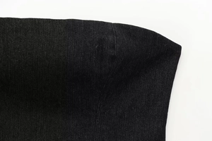 Dettaglio del tessuto denim nero con cuciture precise e trama dell'intreccio
