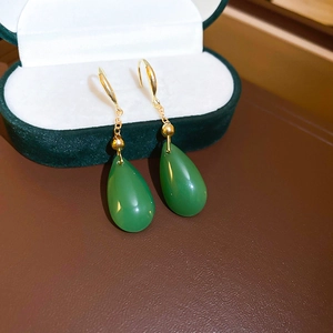 Close-up of gold-plated drop glass zircon earrings with green jade pendant detail
