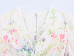 Detail shot of the V-neckline with floral embroidery on white chiffon fabric