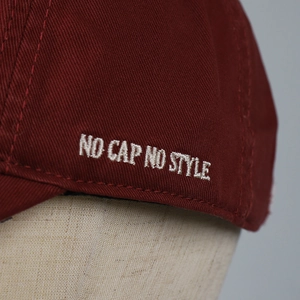 Nahaufnahme der weinroten Baumwollkappe mit weißer No Cap No Style Bestickung