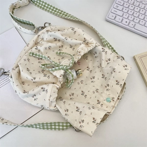 Floral canvas drawstring bag detail with green checkered strap and vintage pattern