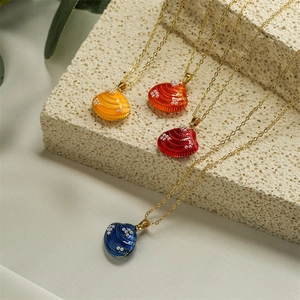 Detalle de cuatro colgantes de concha en esmalte de colores con perlas en cadenas de oro