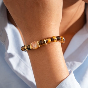 Detail of tiger eye bead bracelet with gold accents on woman's wrist in natural light