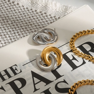 Detail of interlocking two-tone hoop earrings and gold chain necklace on textured background