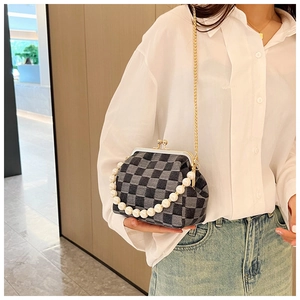 Detail of checkered clasp evening bag with pearl handle and golden chain strap