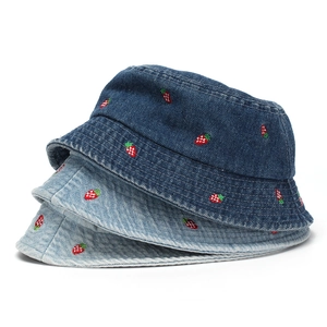 Detail of red strawberry embroidery on distressed denim bucket hats in blue and light blue