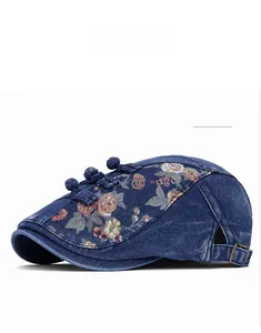 Détail du béret en denim bleu avec imprimé floral, boutons chinois et boucle en métal