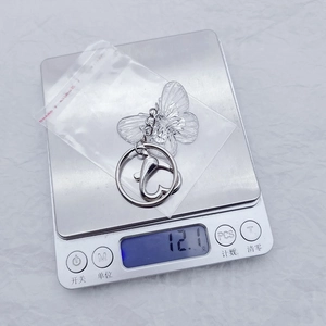 Close-up of the black and white butterfly keychain on a scale showing 12.1g weight