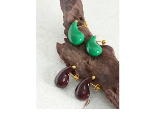 Macro detail of teardrop enamel earrings in green and burgundy with gold studs