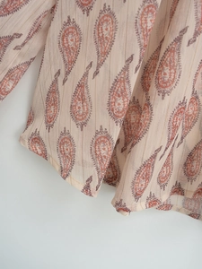 Close-up of paisley print chiffon fabric with shimmering gold metallic stripes and hem detail