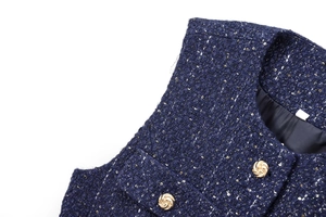 Close-up of navy tweed fabric with sequins and embossed gold buttons on top