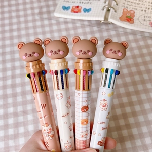 Detail of 4-piece cute bear retractable multi-color ballpoint pens held over a notebook