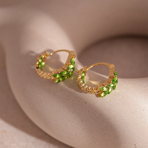 Detail of vintage wheat ear gold hoop earrings featuring marquise green crystals